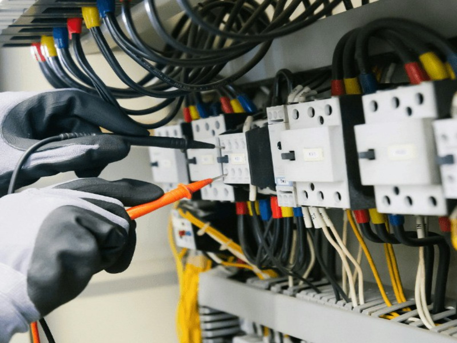 Mains gantées qui testent un tableau électrique